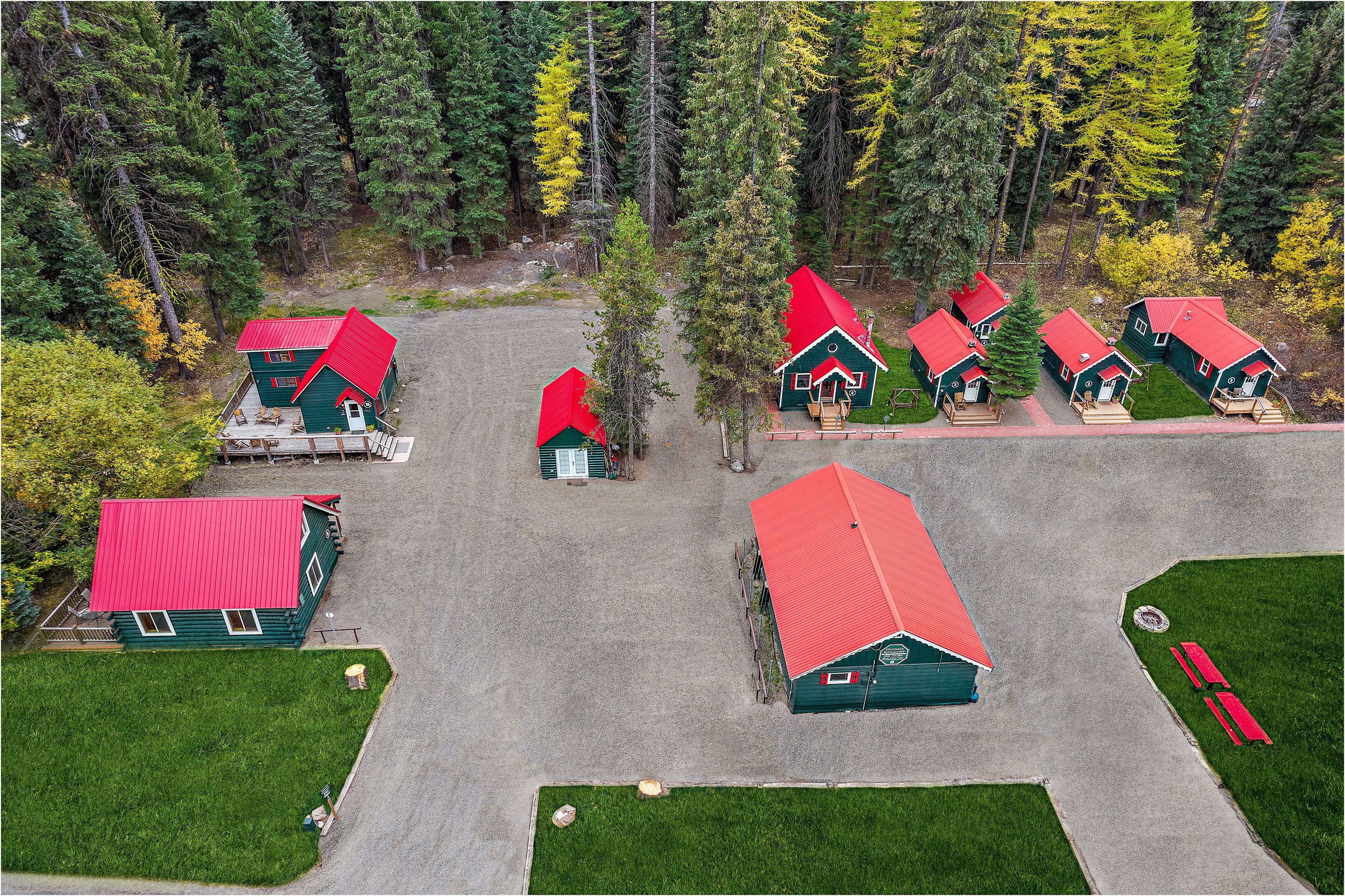 A cluster of cabins with red roofs, surrounded by dense forest.