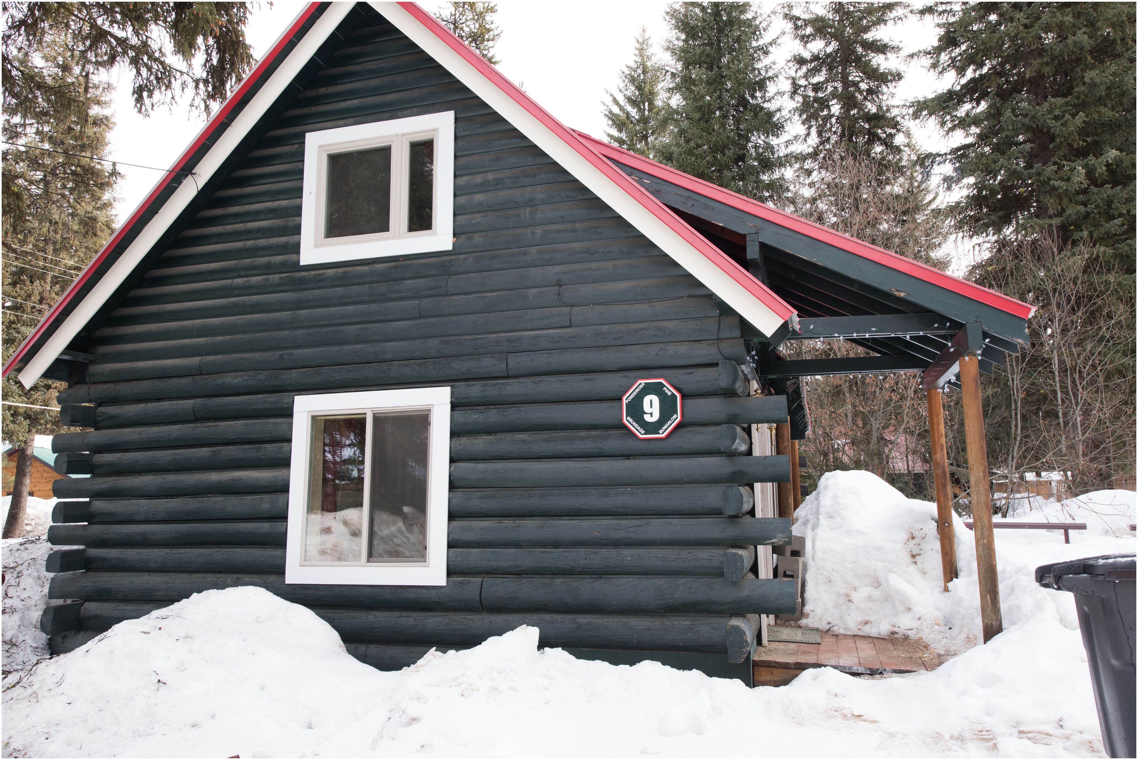 A log cabin with a red roof and a number 9 sign.