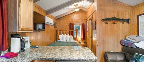 Une petite cabine comprenant un coin cuisine, une table à manger, un lit et une banquette intégrée.