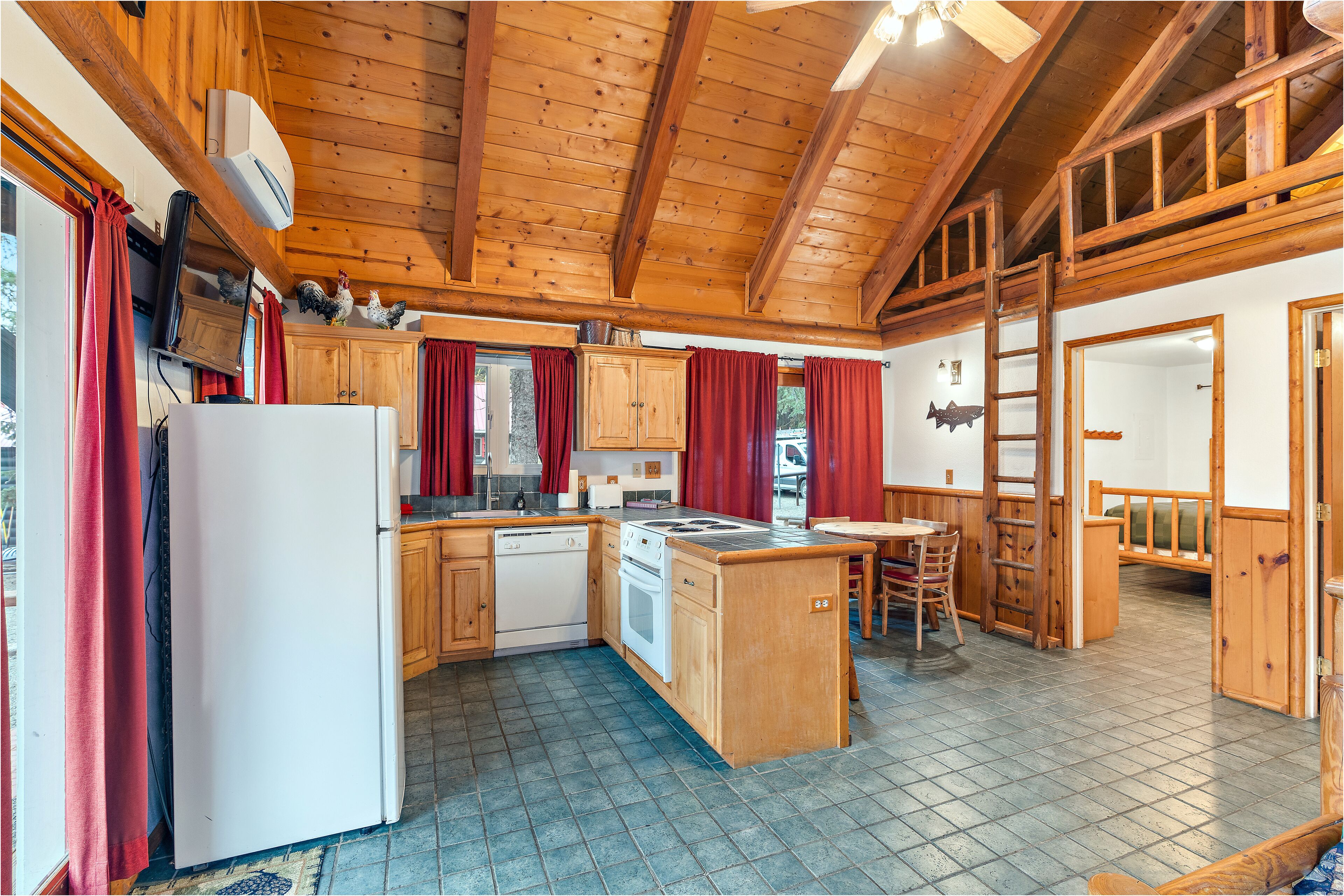 A kitchen with wooden cabinets, a refrigerator, a stove, and a dining area with a table and chairs.