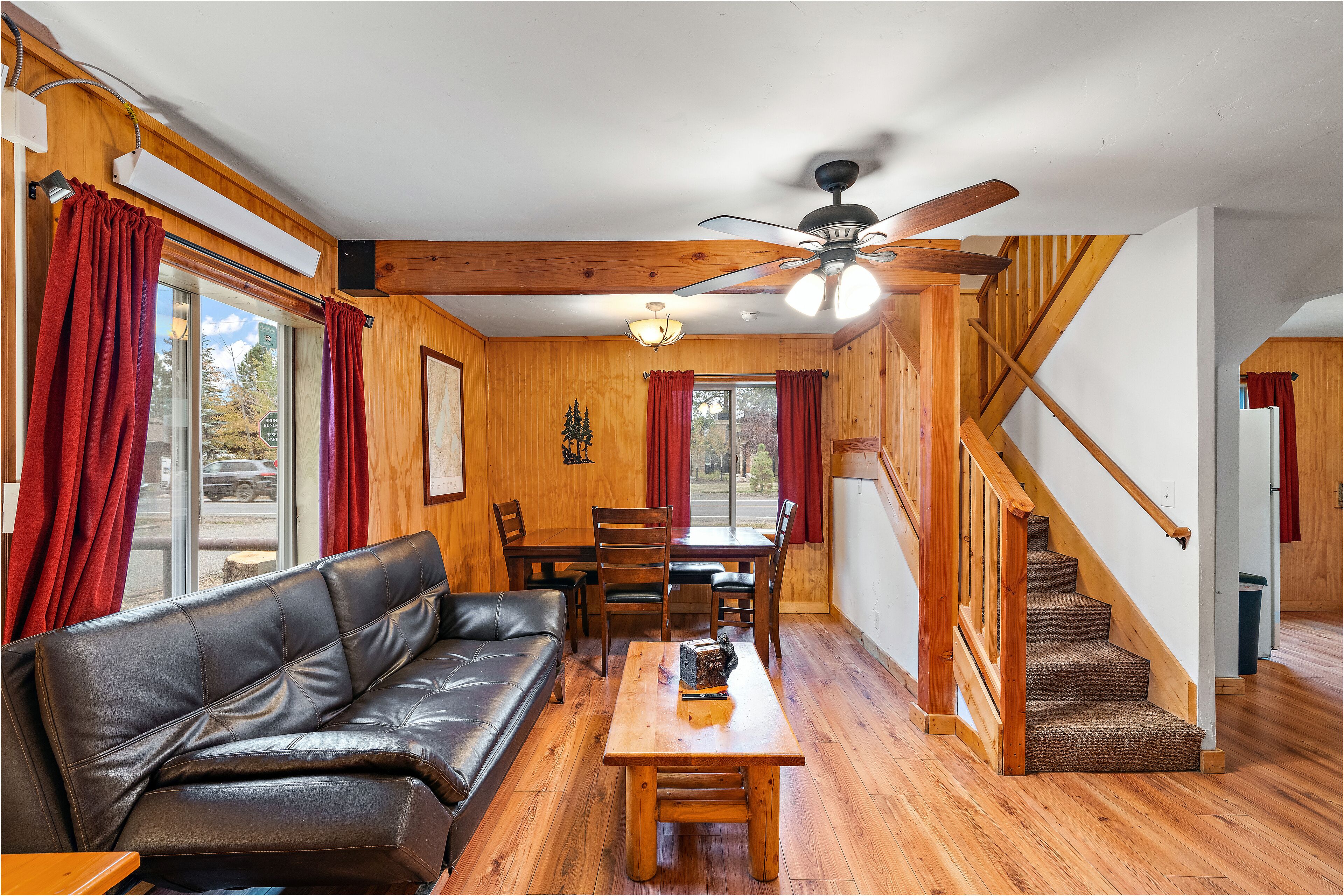 A cozy living room with a leather sofa, wooden dining table, and a staircase.