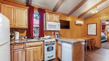 Una cocina con armarios de madera, estufa, microondas y lavavajillas.