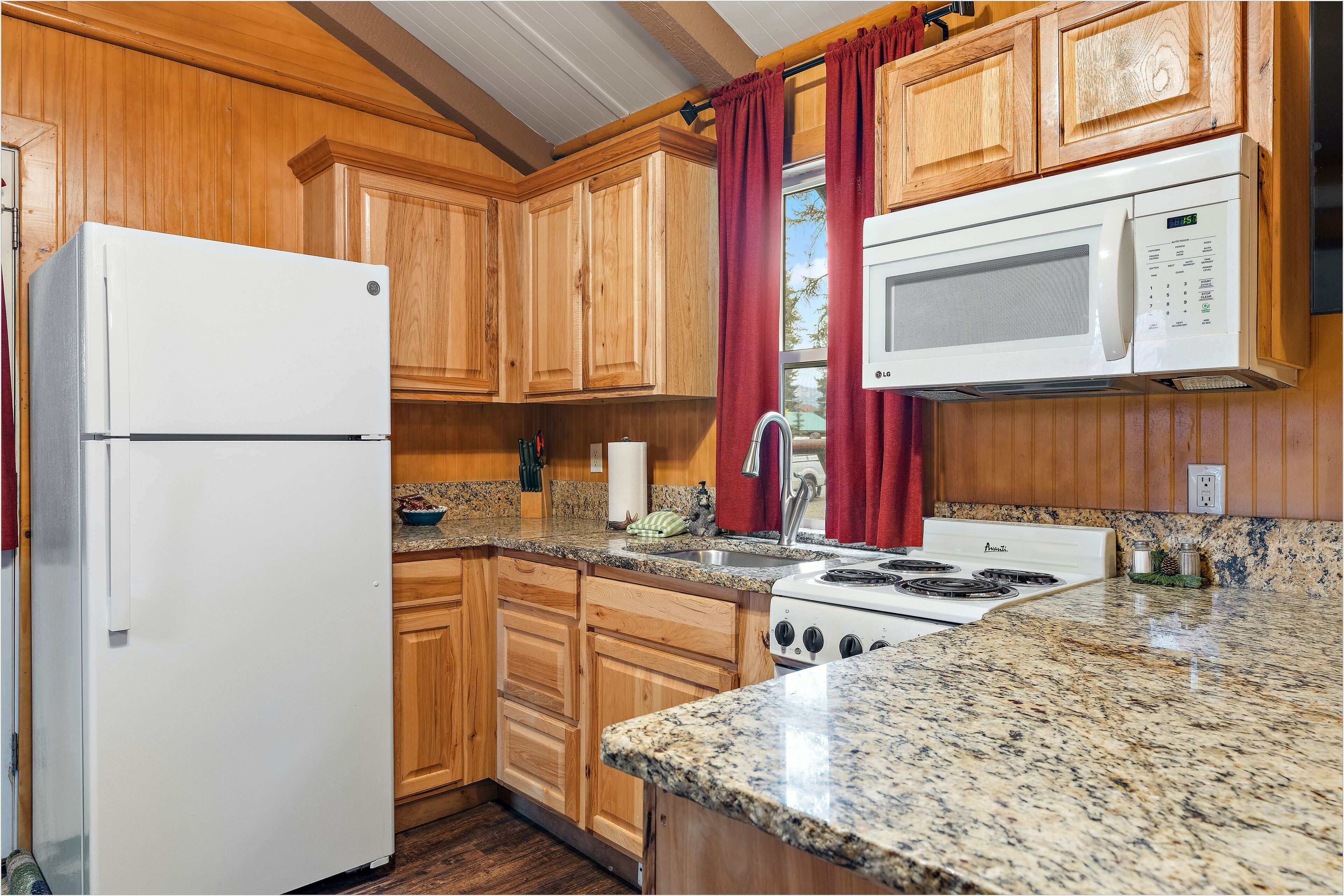 A kitchen with wooden cabinets, a white refrigerator, a stove, and a microwave.