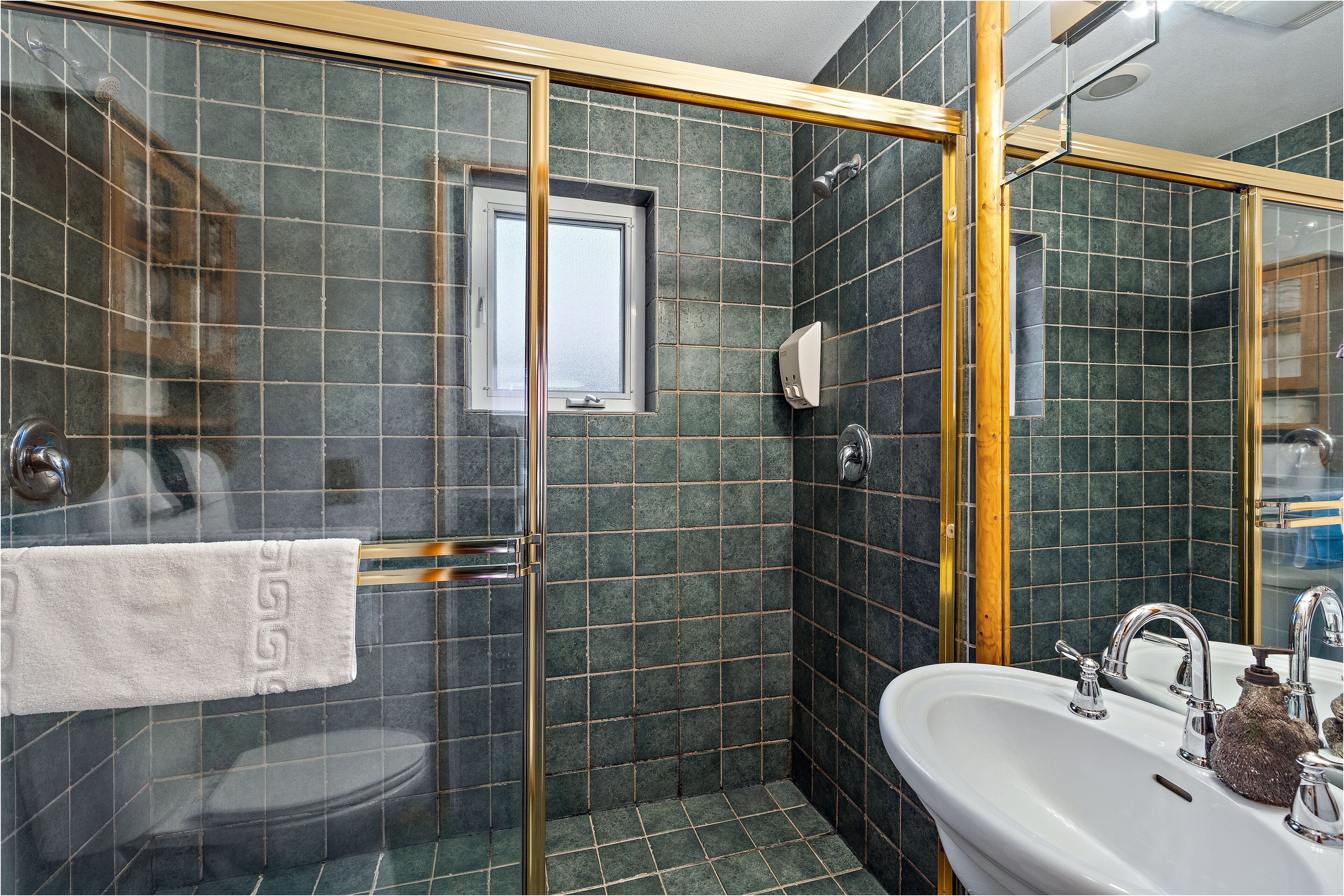 A bathroom with a glass shower enclosure, a sink with a mirror, and a towel rack.