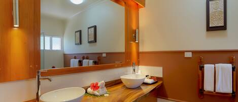 A bathroom with a wooden vanity, a large mirror, a white sink, and a towel rack.