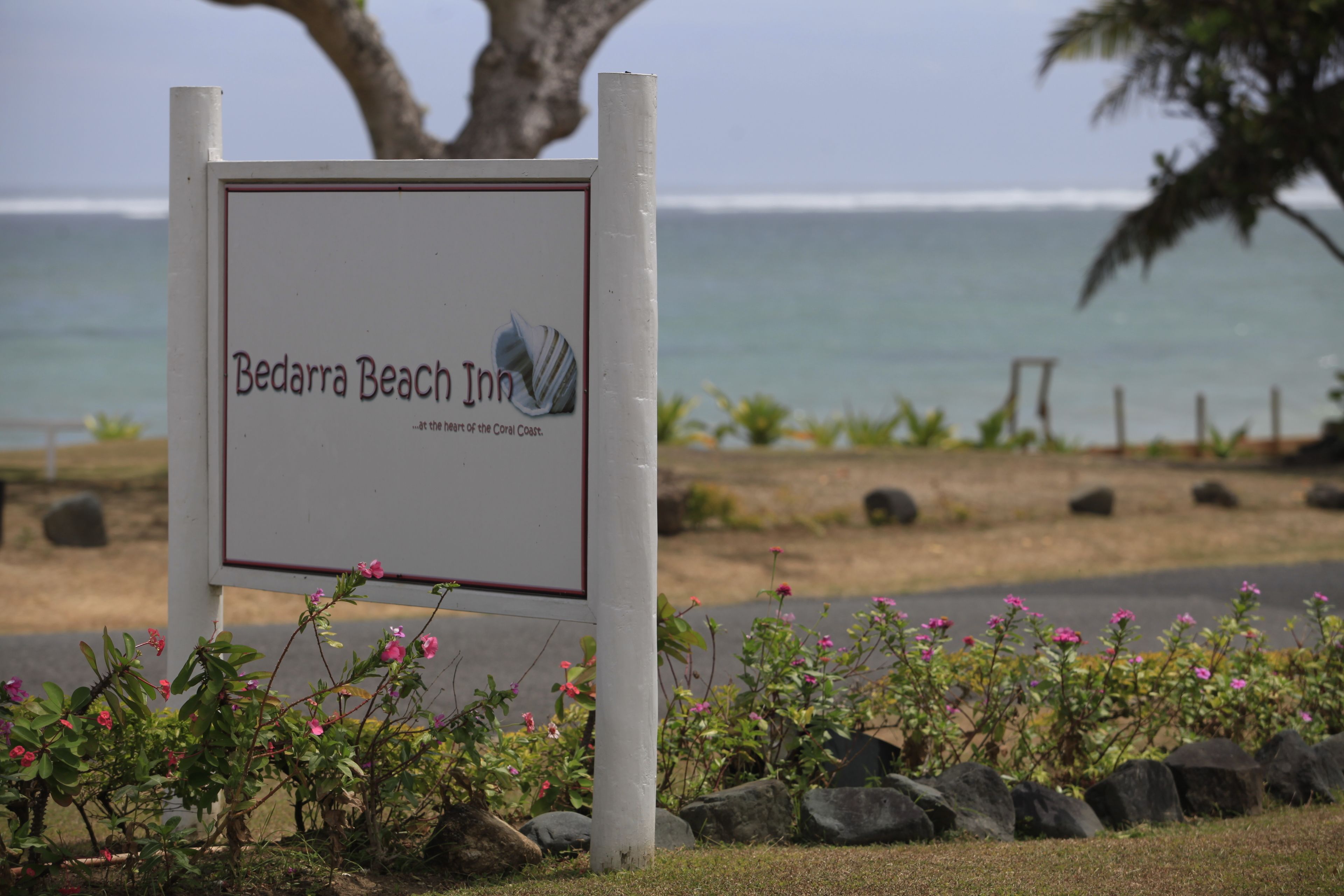 Naamplaatje voor Bedarra Beach Inn, met uitzicht op de oceaan op de achtergrond.