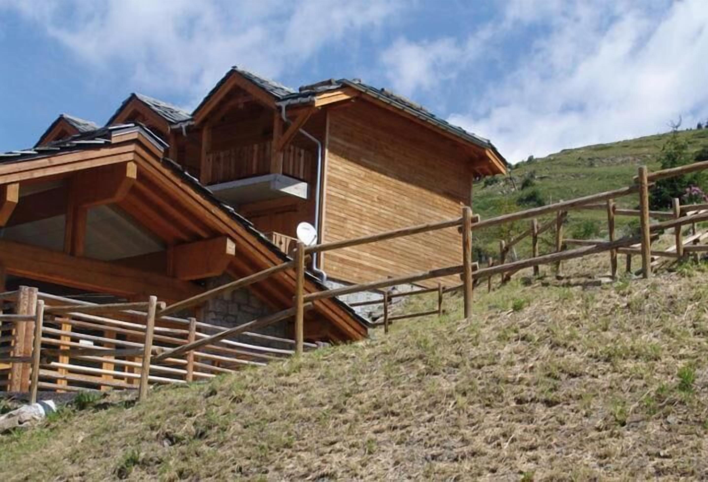 A wooden chalet with a balcony and a wooden fence.