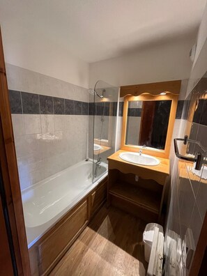 A modern bathroom with a glass-enclosed shower, a wooden vanity with a sink, and a large mirror above the vanity. - Résidence Lagrange Vacances Le Grand Panorama II (Valmeinier)