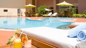 A poolside lounge with a wooden deck, lounge chairs, and umbrellas. - ParkView Hotel (Hue)