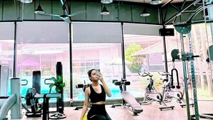 A gym with exercise equipment, a large mirror, and a motivational sign. - ParkView Hotel (Hue)
