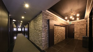 A hallway with a carpeted floor, brick walls, and doors labeled "Lobby" and "Exit." - Hotel Kobos (Seoul)