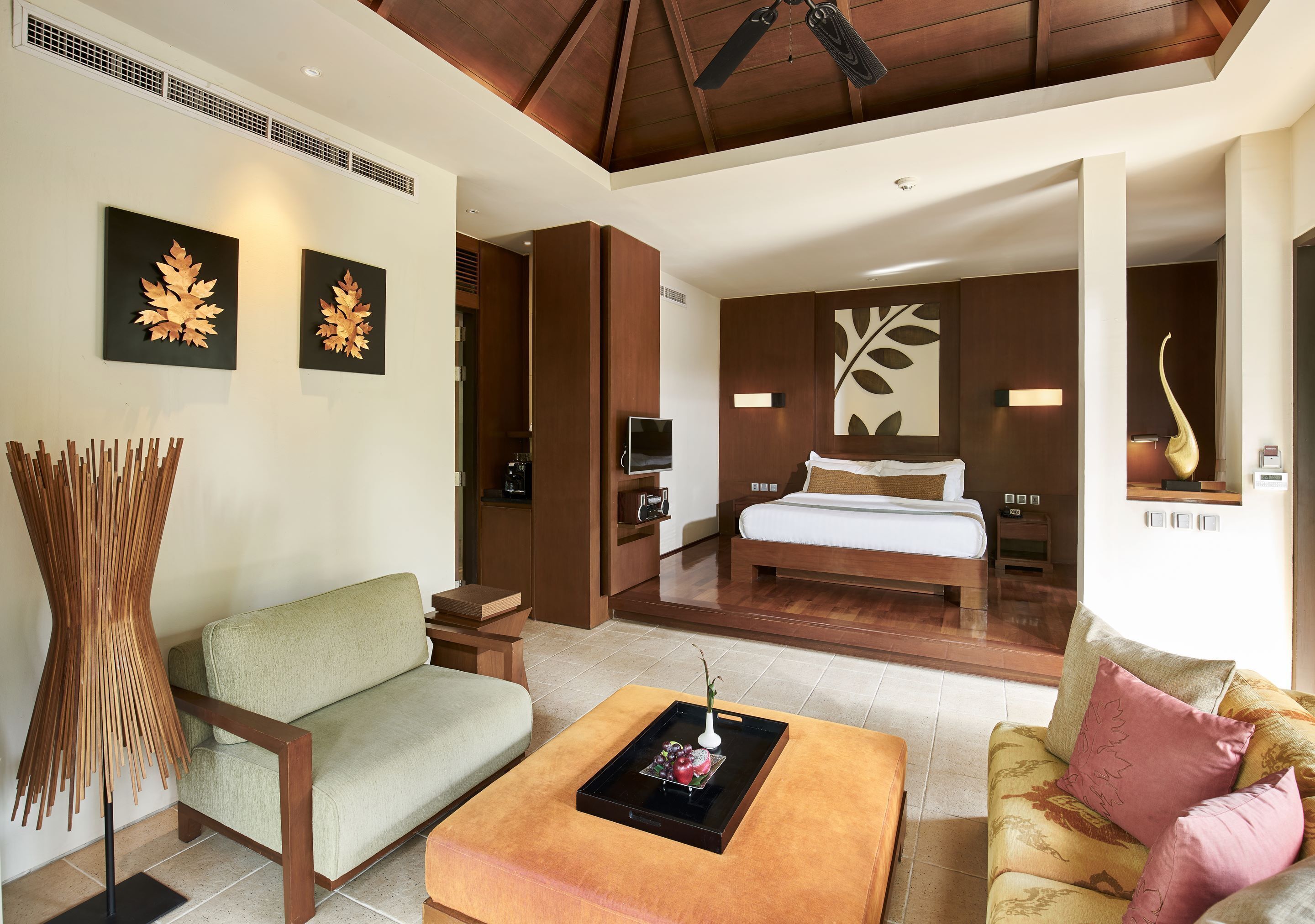 A modern hotel room with a sofa, a coffee table, a bed, and a TV.
