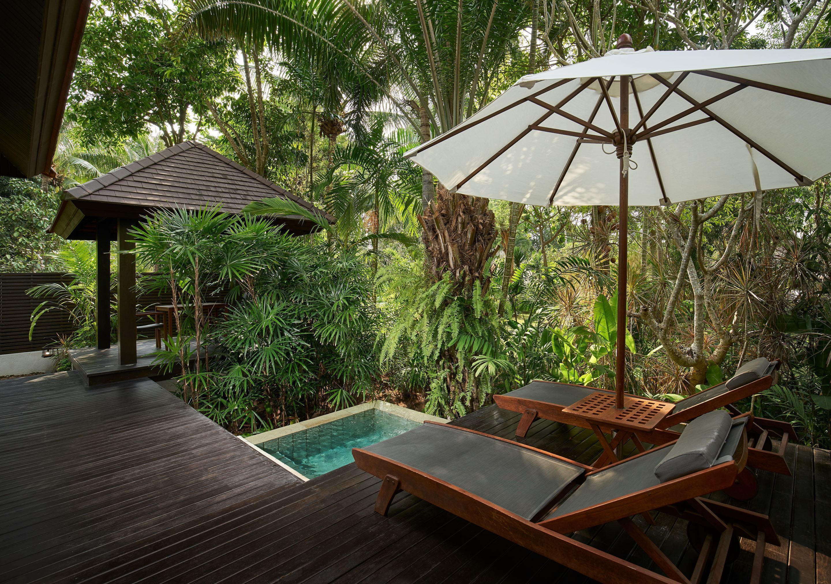 A wooden deck with a pool, lounge chairs, and an umbrella.