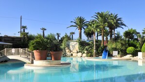 Una piscina con un puente, palmeras y un muro de piedra.