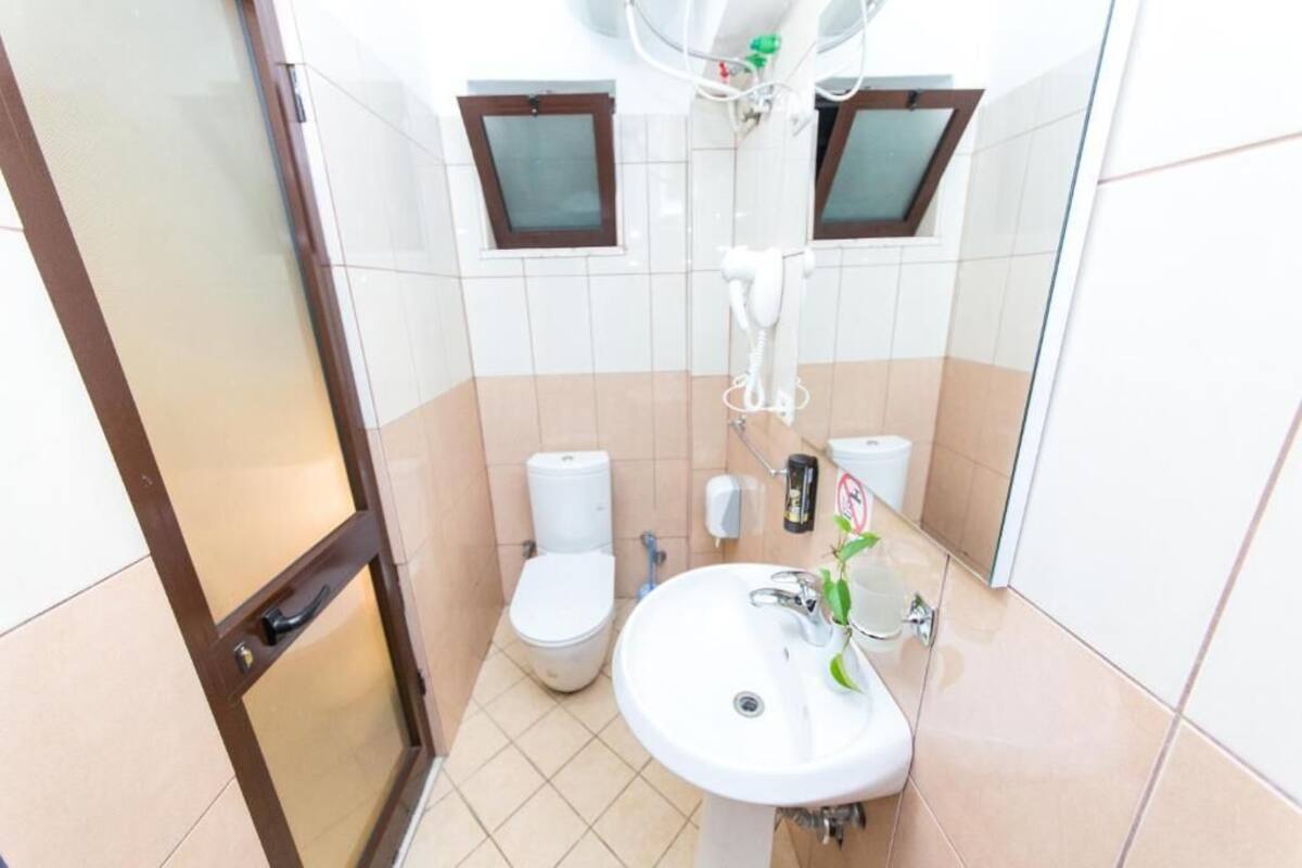 A bathroom with a toilet, sink, and mirror.