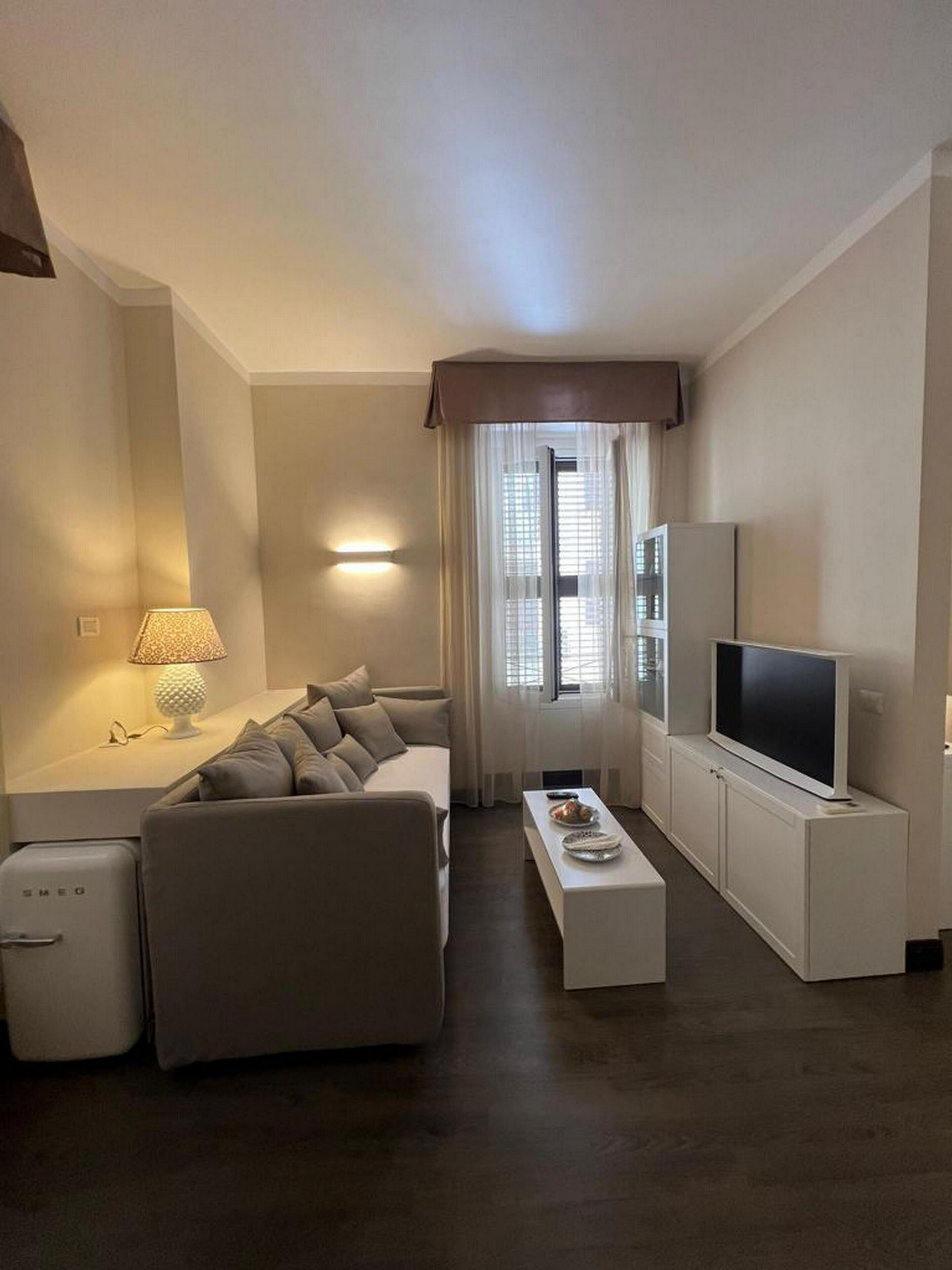 A modern living room with a sofa, a coffee table, a TV, and a lamp.