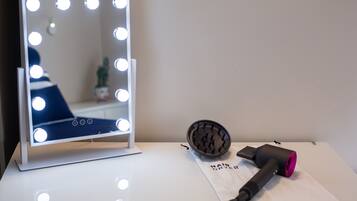A vanity with a mirror and lights, a hair dryer, and a bag labeled "Hair Dryer".