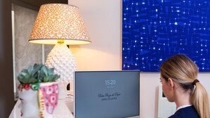 A hotel room with a desk, a computer, a decorative lamp, and a wall art piece. - Relais Piazza Del Popolo - Aminta Collection Luxury Rooms (Rome)