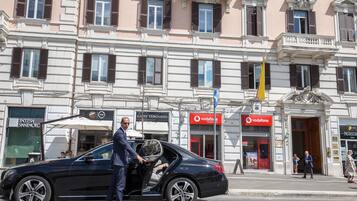 Un coche negro estacionado en una calle, con un hombre que sale del vehículo.