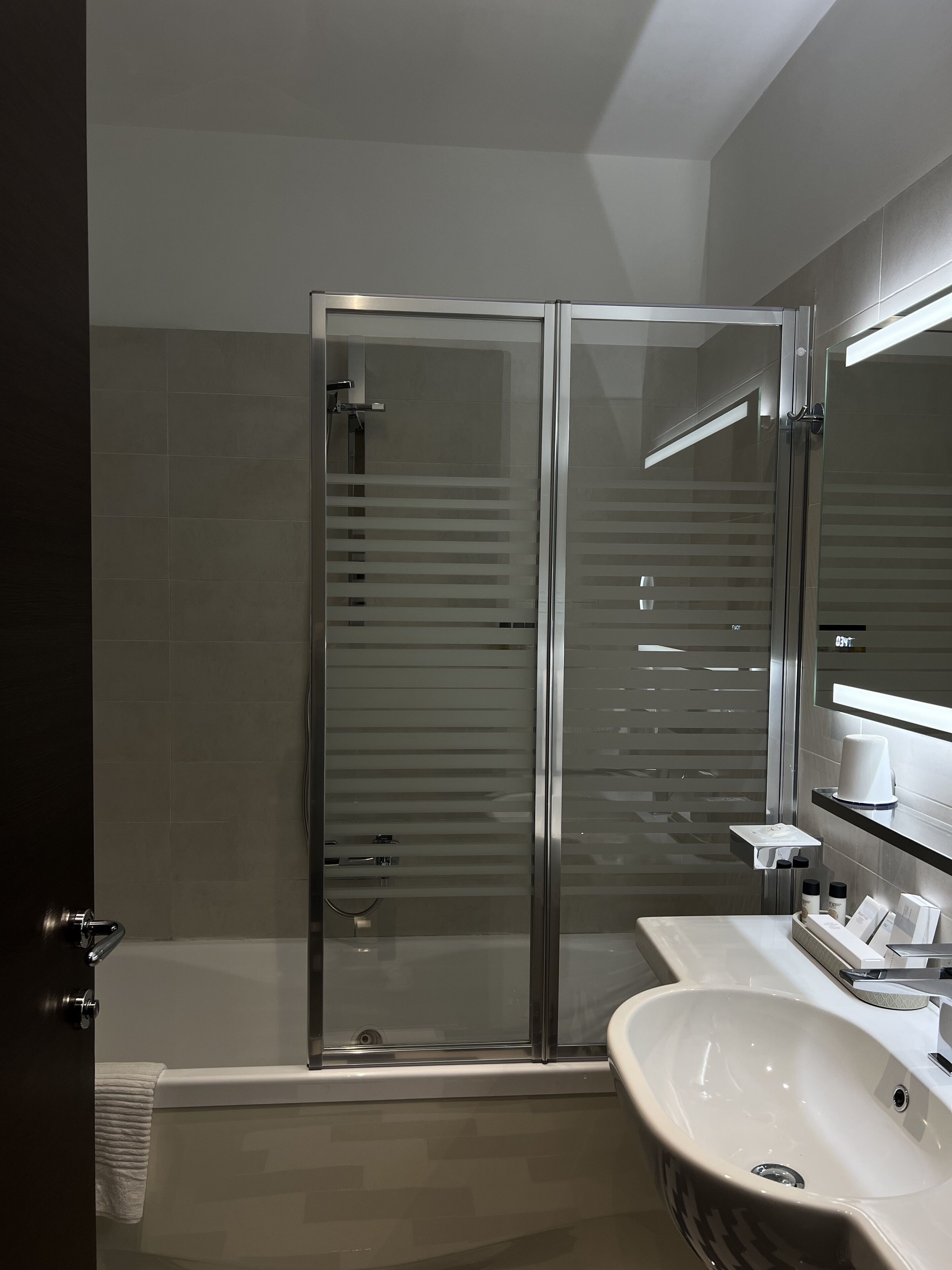 A modern bathroom with a glass-enclosed shower, a white sink, and a mirror above the sink.