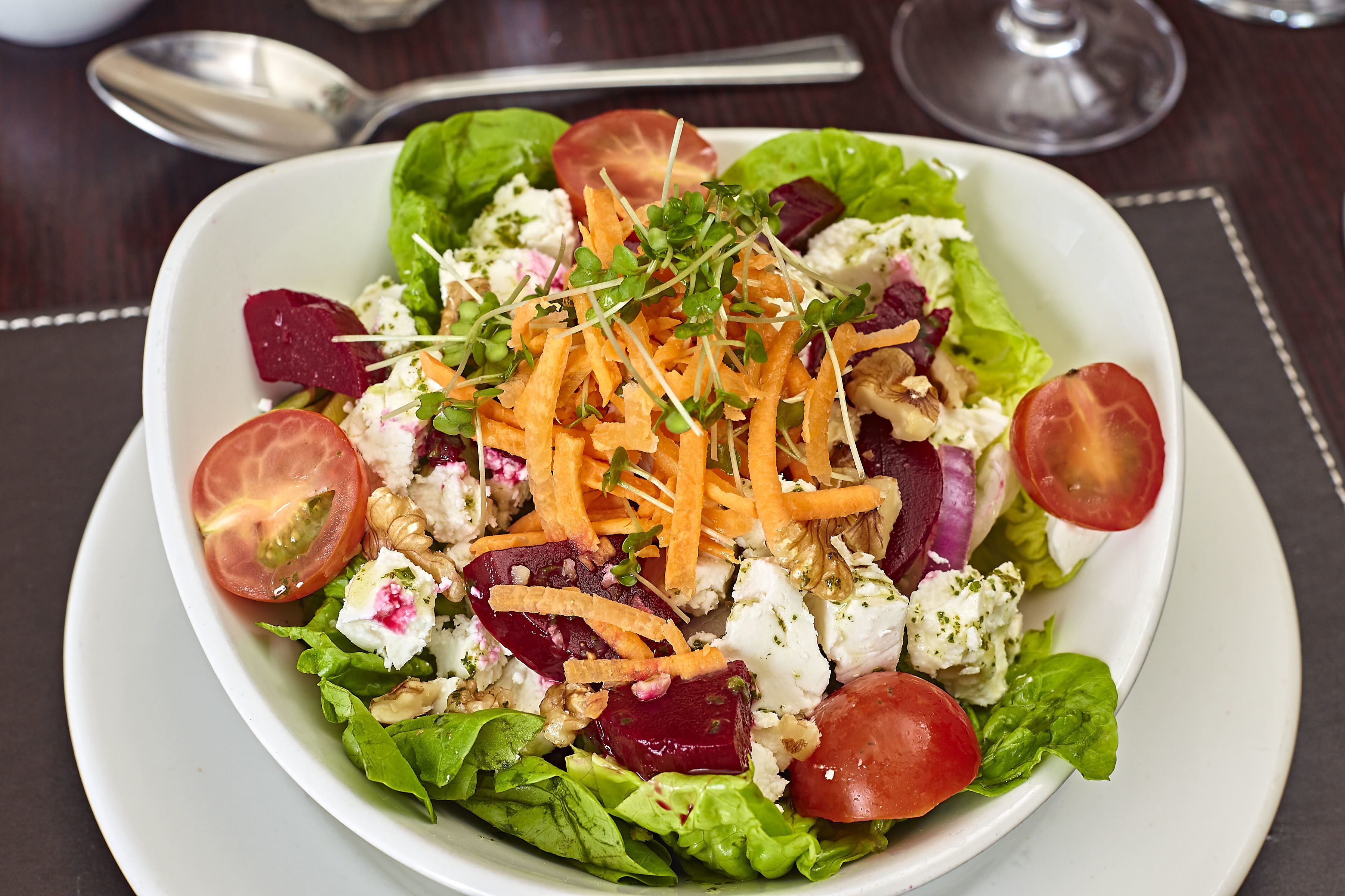 A salad with various vegetables and nuts on a white plate.