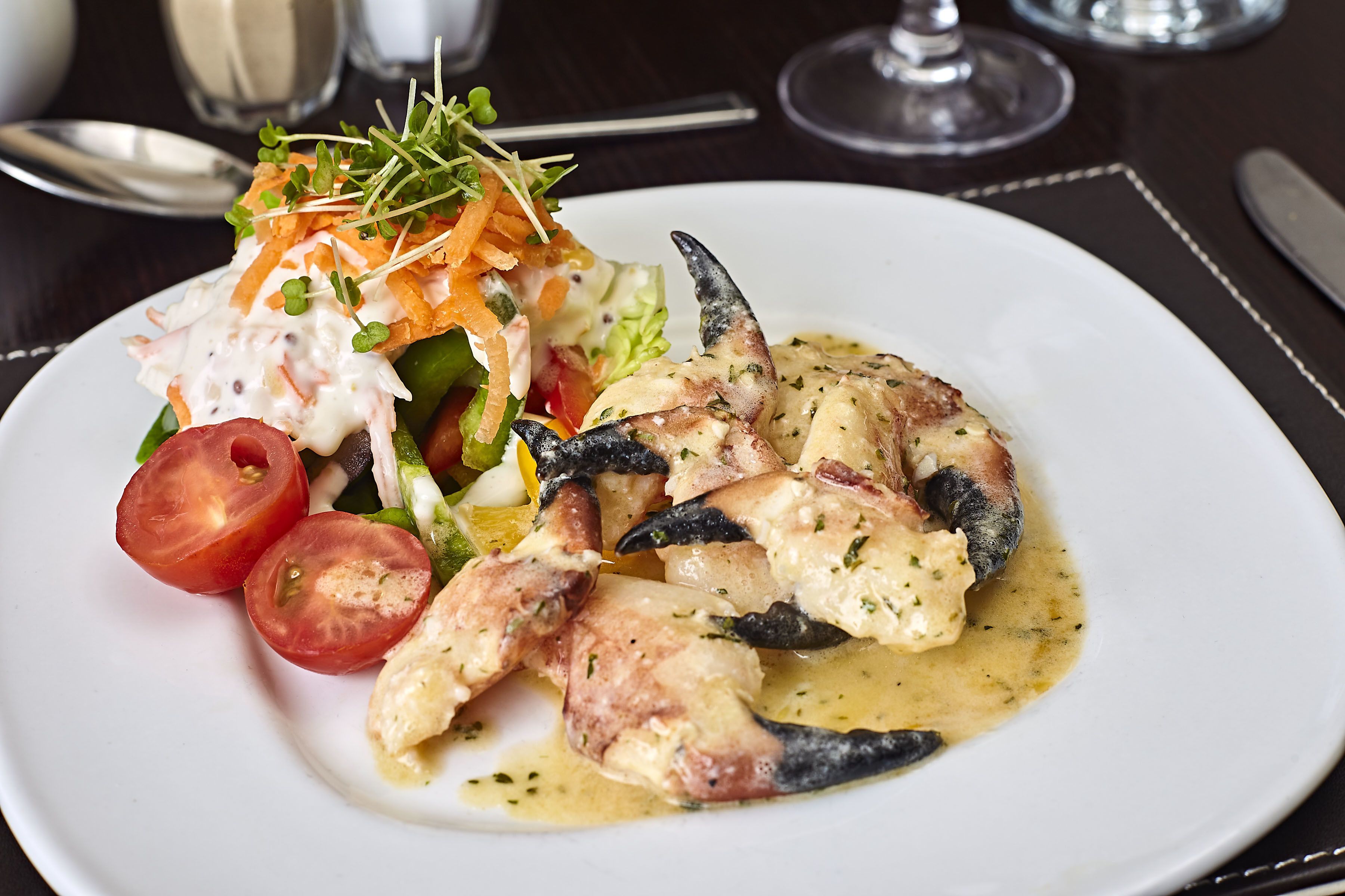 A plate of food with a salad, tomatoes, and a creamy sauce.