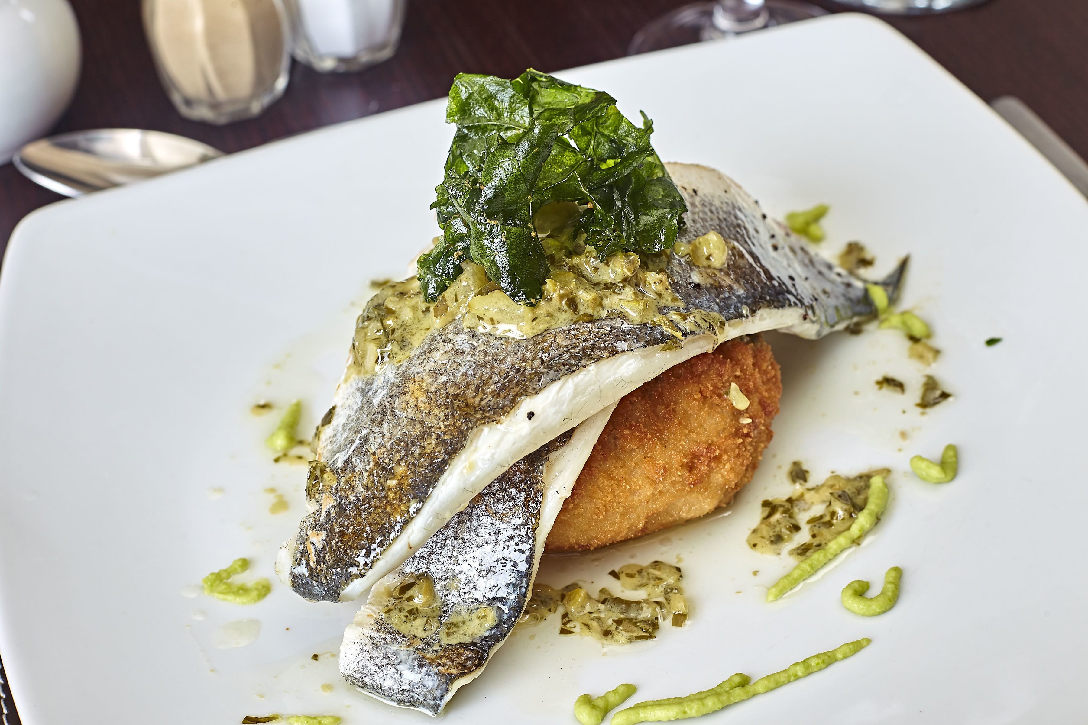 Un plato con pescado, verduras y salsa.