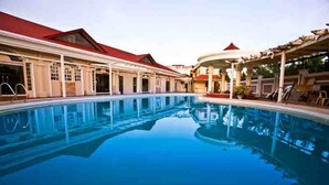 A swimming pool with a covered area and lounge chairs. - Hotel Venezia (Legazpi)