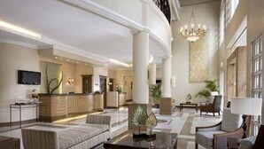A spacious lobby with a reception desk, seating area, and a chandelier. - Hotel Venezia (Legazpi)