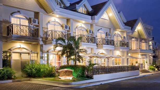A multi-story hotel with balconies, a well-lit entrance, and a landscaped garden. - Hotel Venezia (Legazpi)