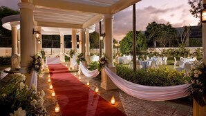 An outdoor wedding venue with a red carpet, white draped columns, and tables set for guests. - Hotel Venezia (Legazpi)
