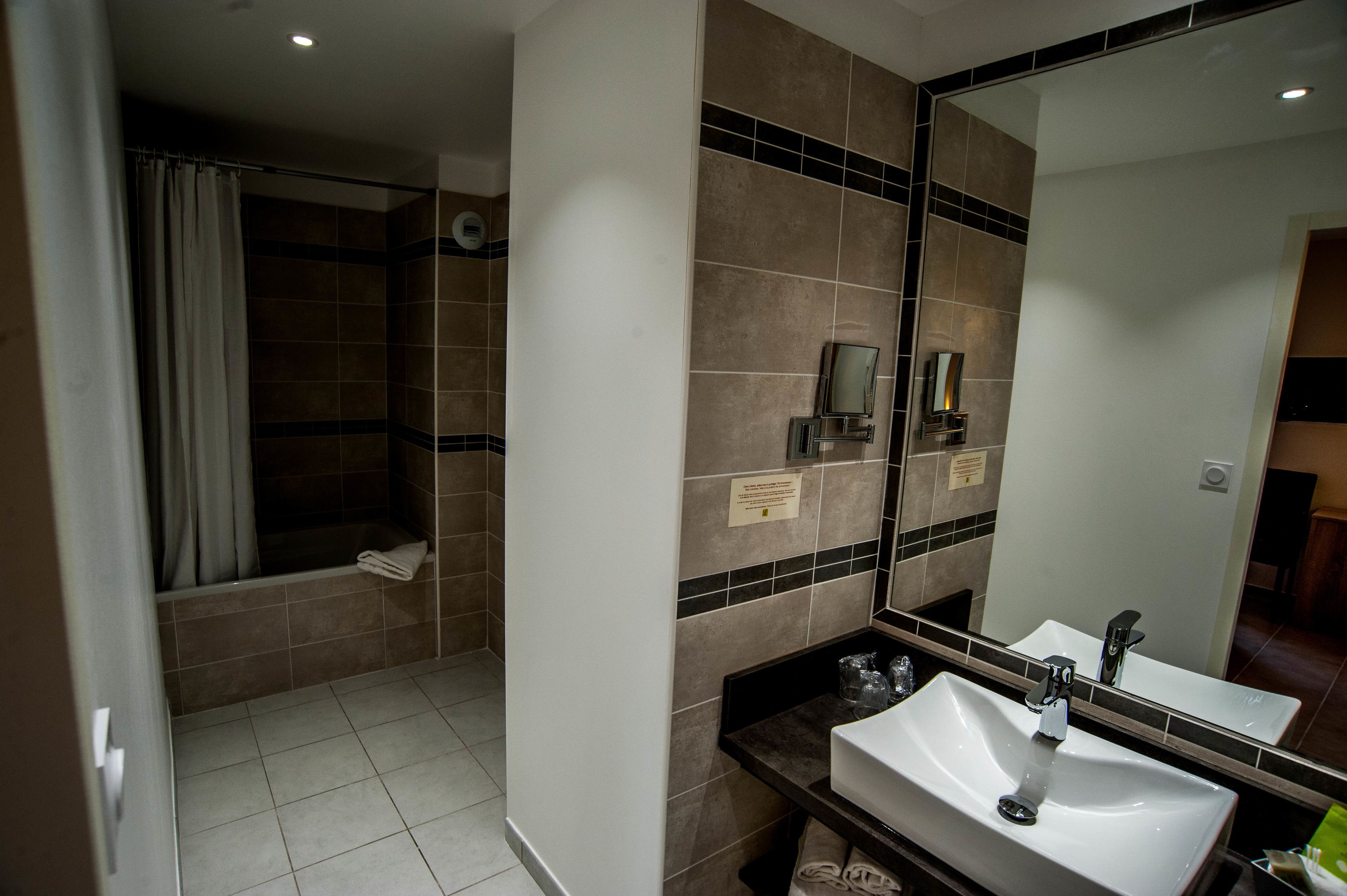 Un baño con bañera, lavamanos, espejo y ducha.