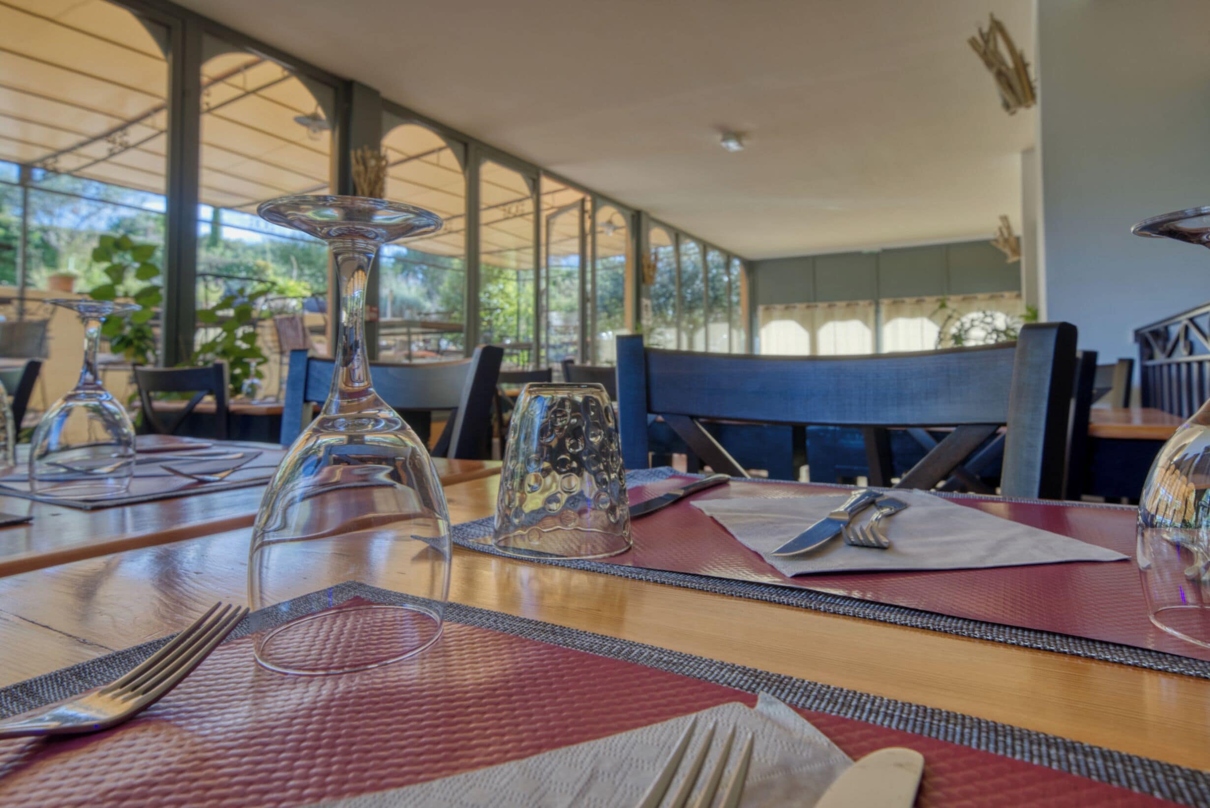 A dining table set with a clear glass, a metal pitcher, and a napkin.
