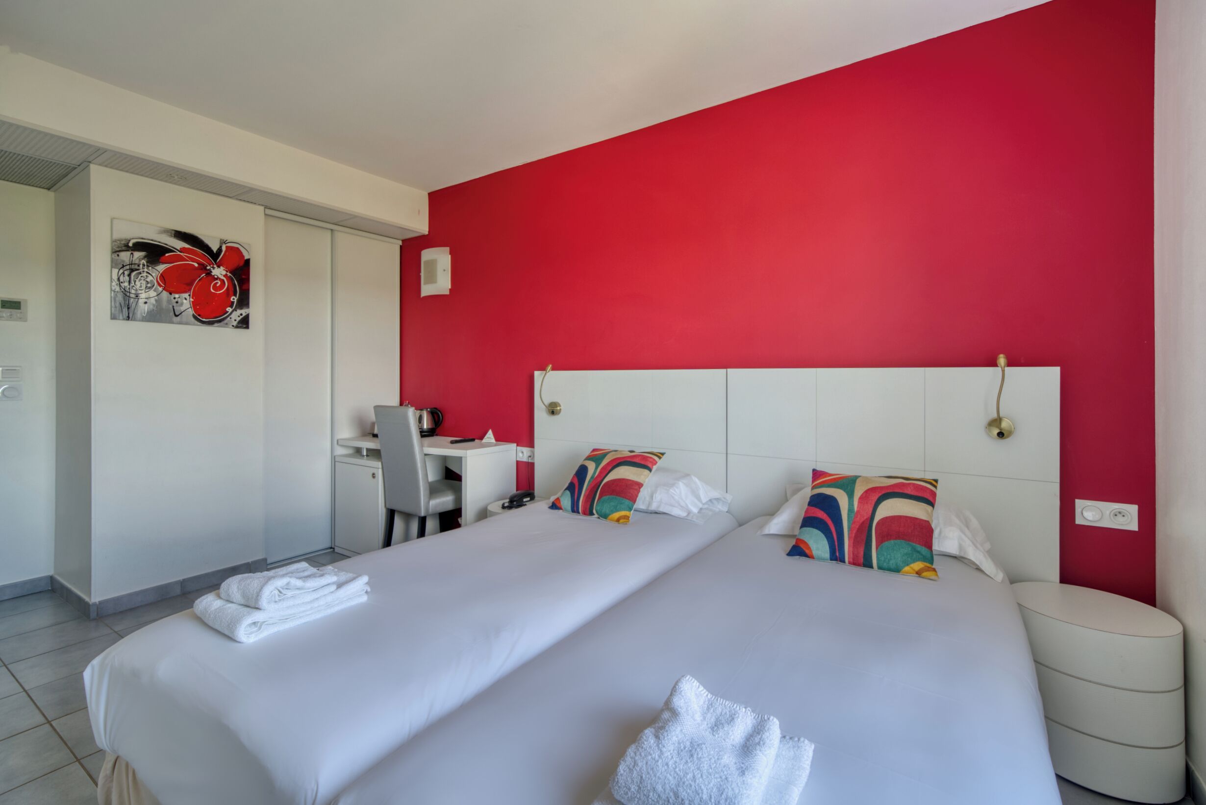 A hotel room with two beds, a desk, and a chair.