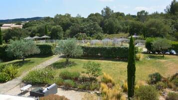 Un jardin aménagé avec des allées, un espace de repos et une aire de jeux clôturée.