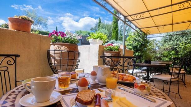 Un desayuno al aire libre con una mesa, sillas y diversas opciones de comida.