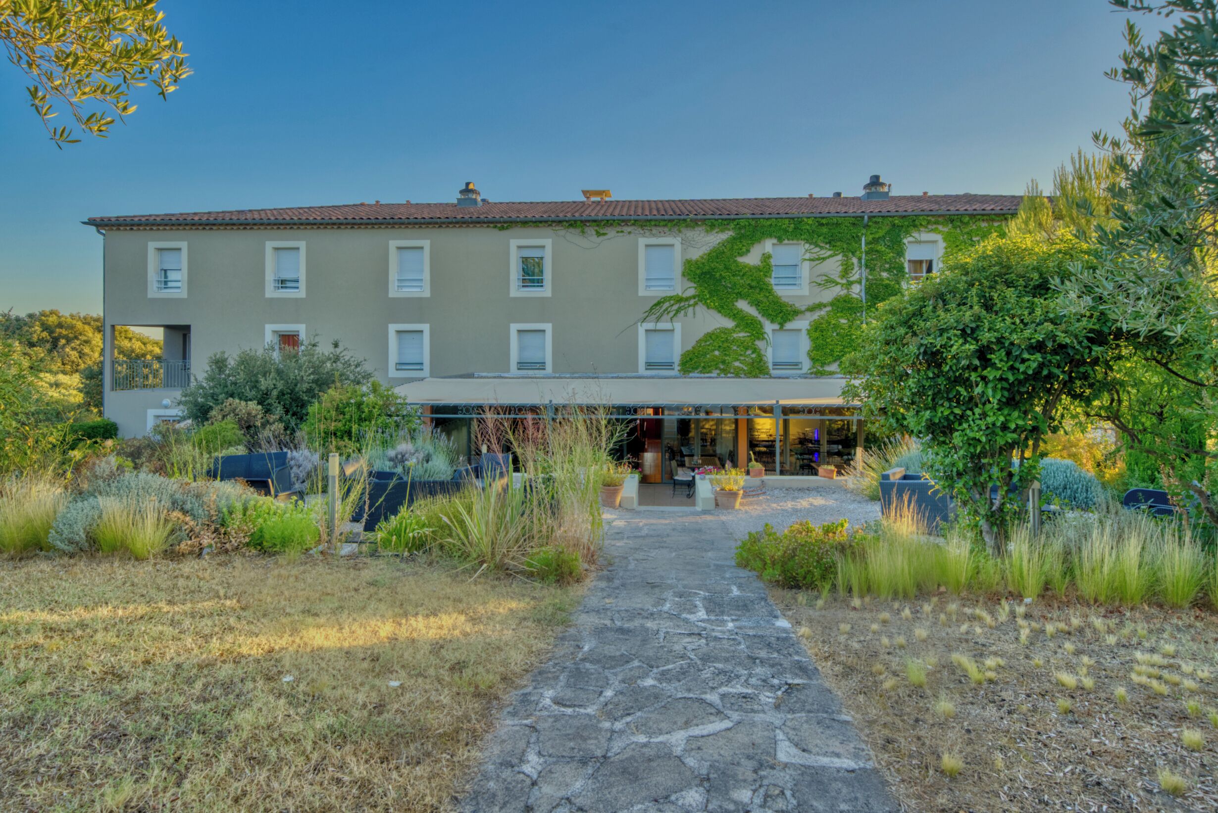 A two-story building with a paved entrance and a garden in front.