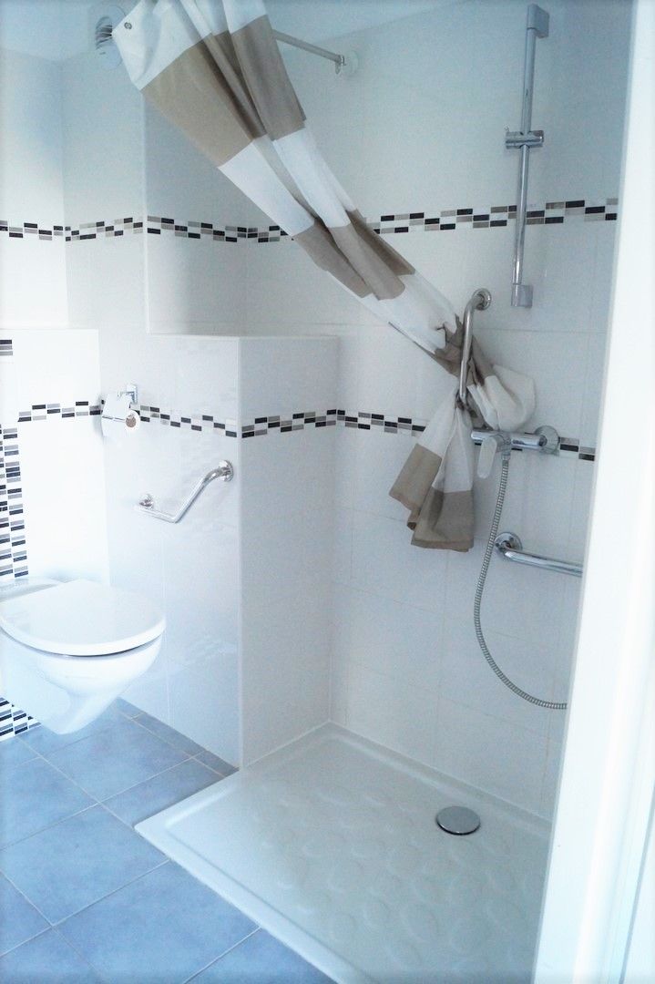 Une salle de bain avec douche, toilettes et lavabo.