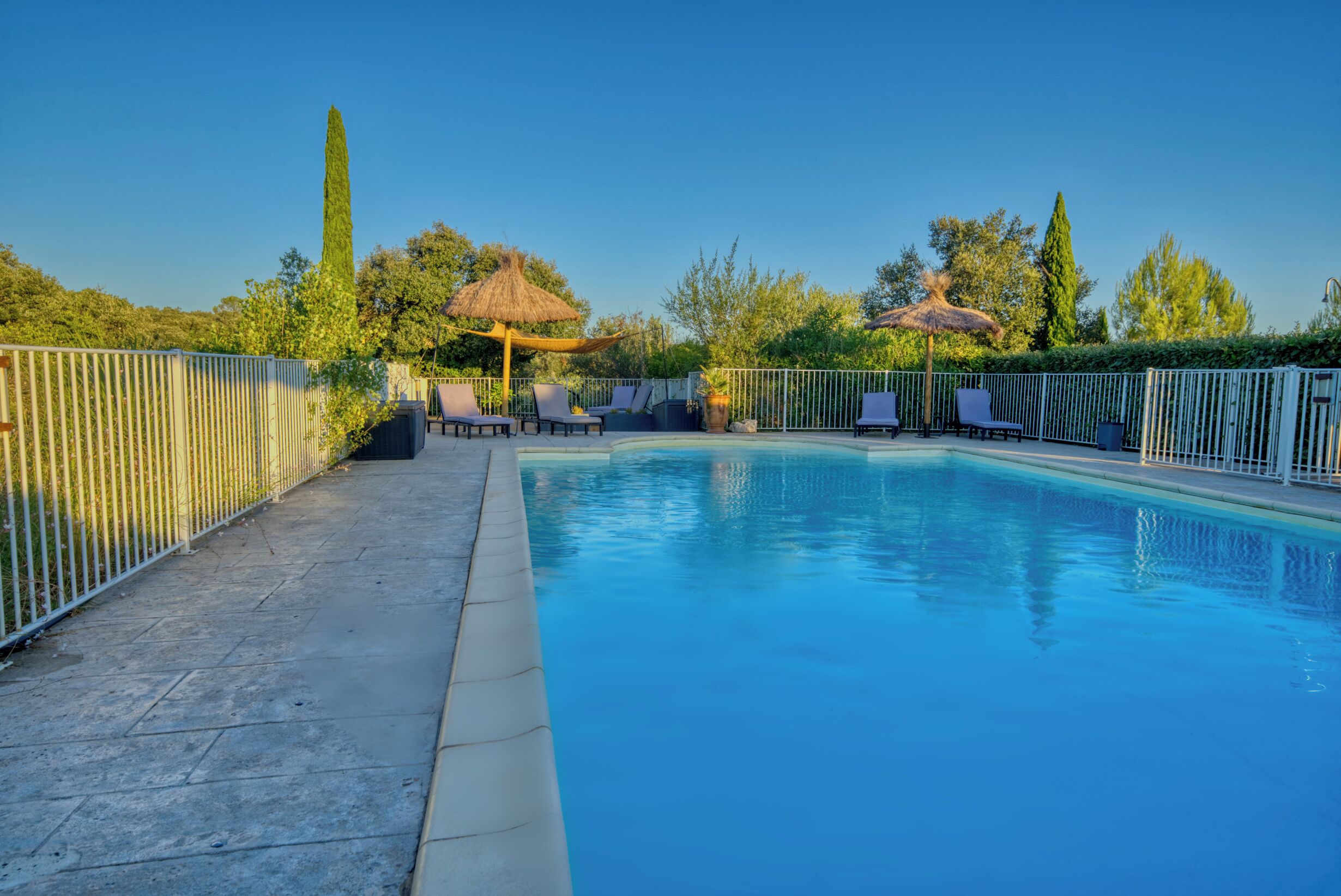 Una piscina al aire libre, sombrillas, tumbonas