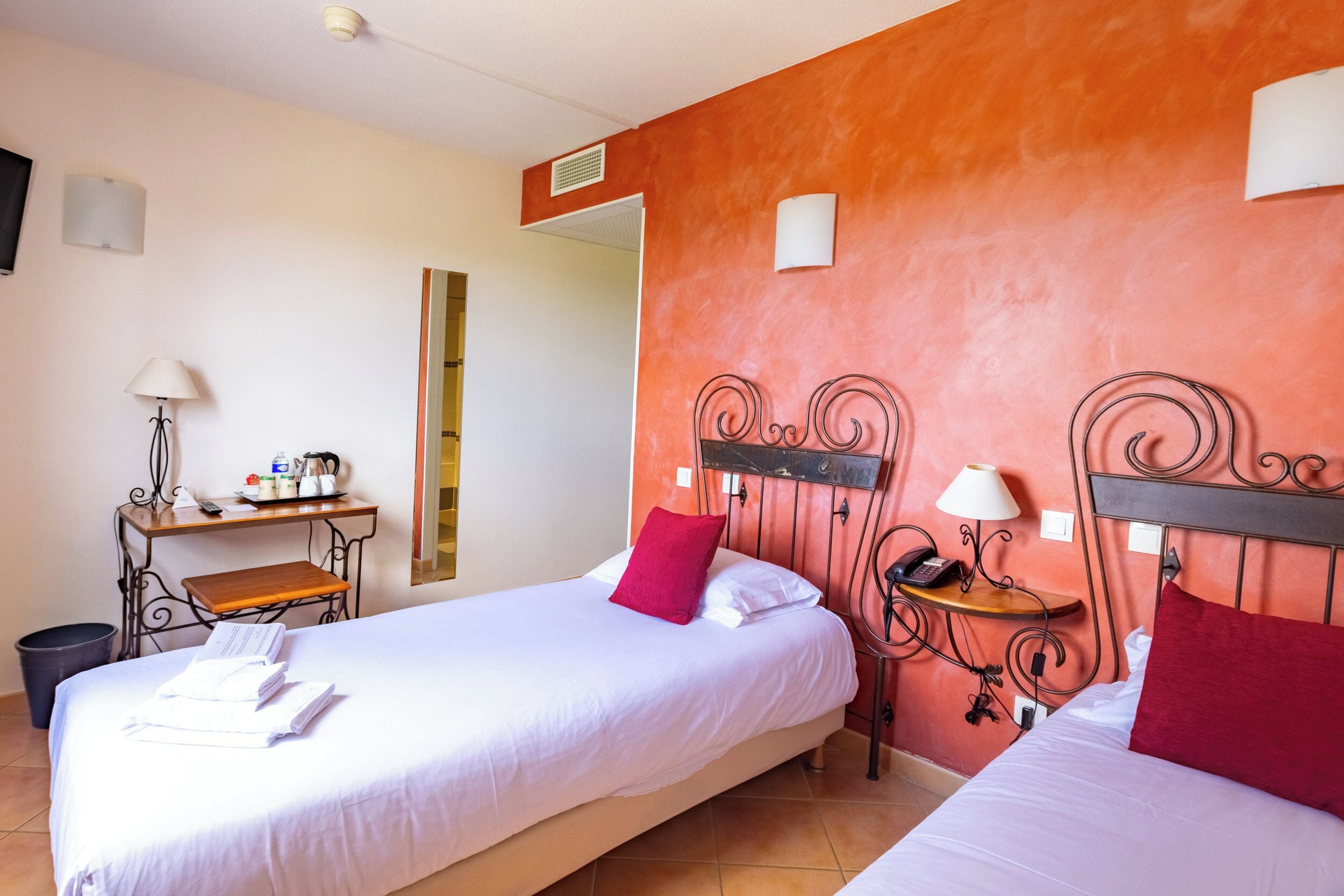 Habitación de hotel con dos camas, un escritorio y un espejo.