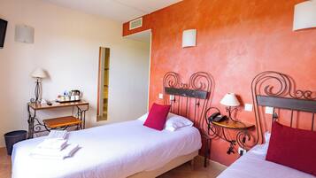 Habitación de hotel con dos camas, un escritorio y un espejo.