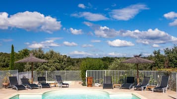 Een buitenzwembad, parasols bij het zwembad en ligstoelen