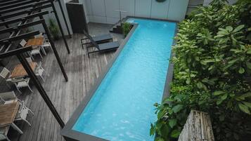 A rectangular pool with a wooden deck and lounge chairs.