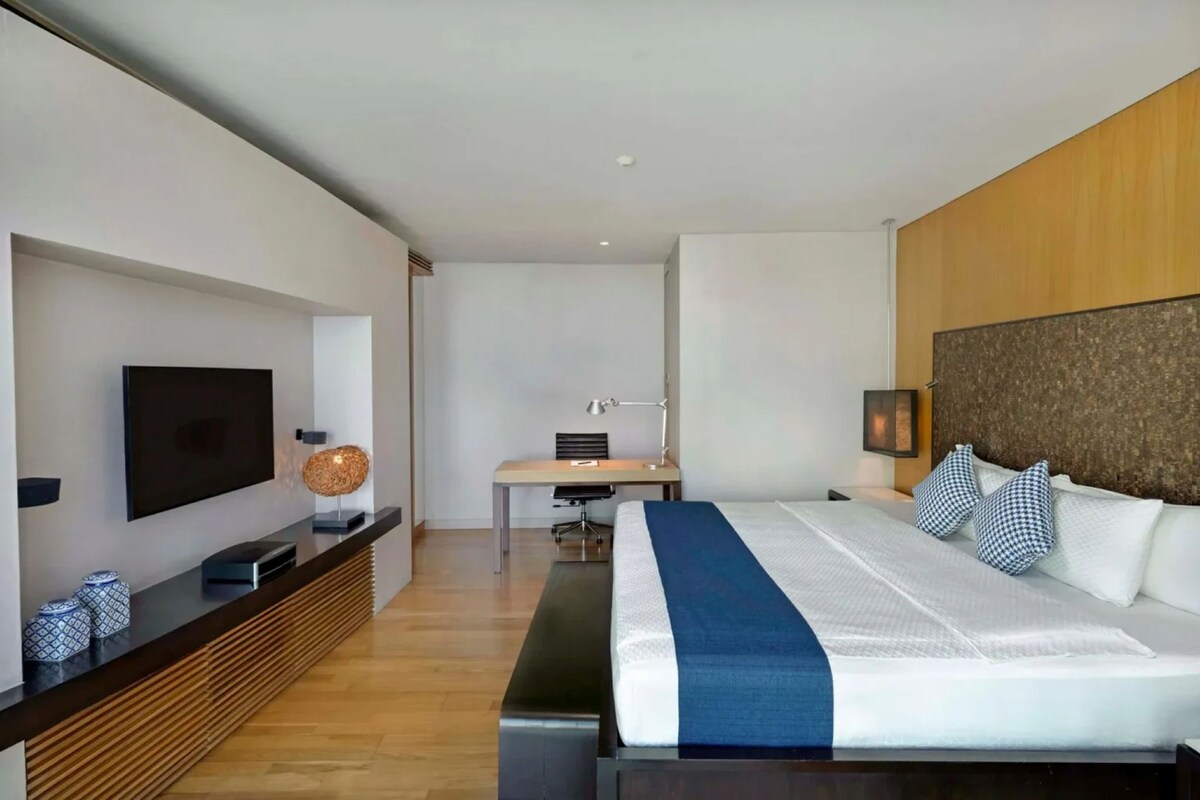 Een moderne hotelkamer met een groot bed, een bureau, een televisie en een houten accentmuur.