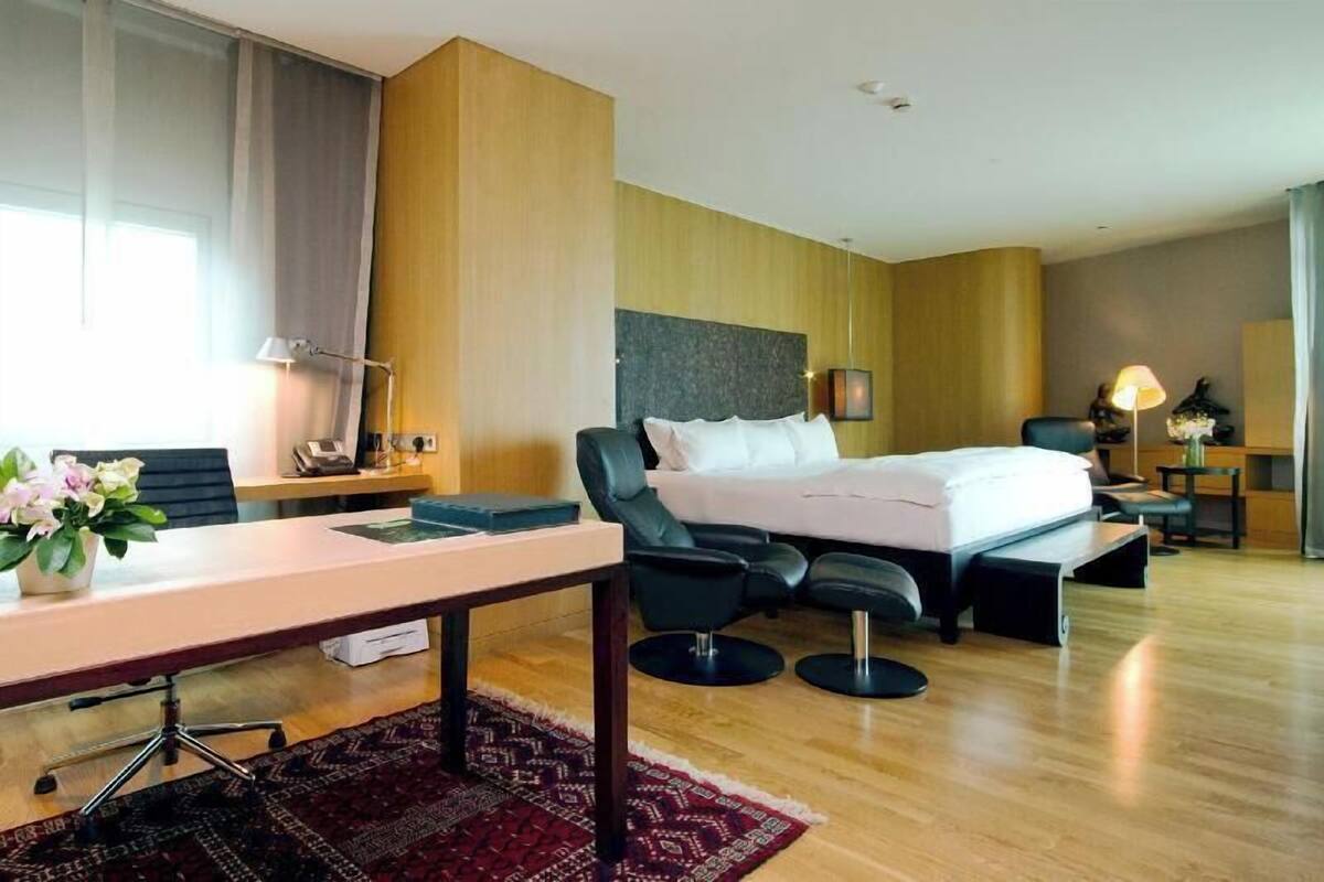 Une chambre d’hôtel avec un lit, un bureau, des chaises et une petite table.