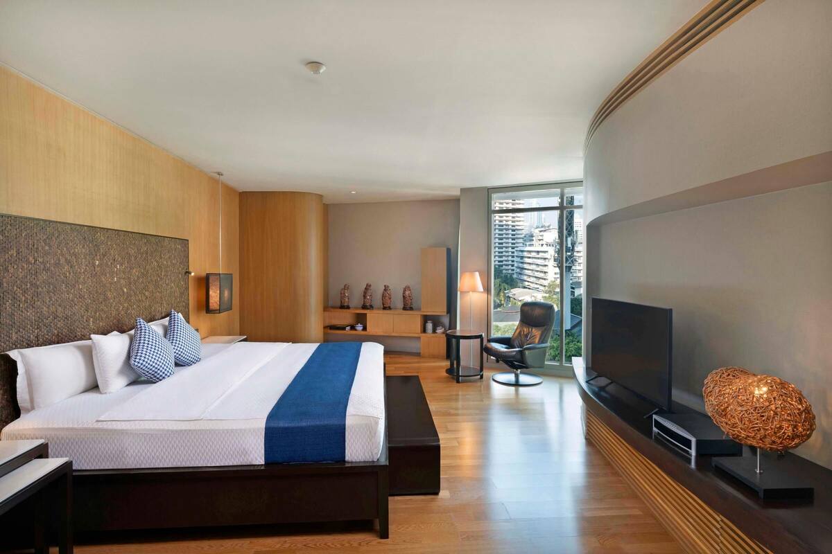 Une chambre d’hôtel moderne dotée d’un grand lit, d’une télévision, d’un coin salon et offrant une vue sur la ville.