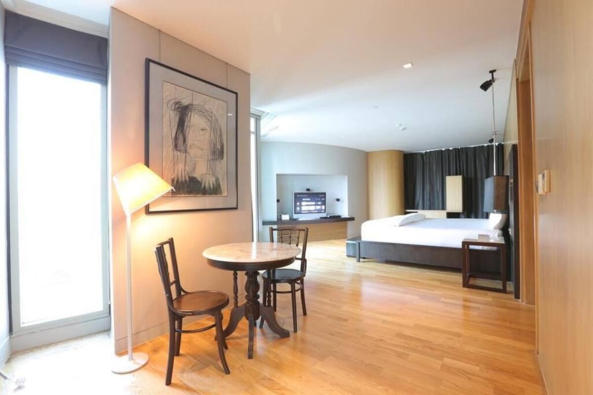 Une chambre d’hôtel avec un lit, un bureau, une chaise, une lampe et un tableau au mur.