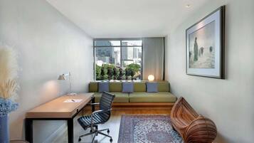 A modern living room with a sofa, a desk, a chair, and a patterned rug.