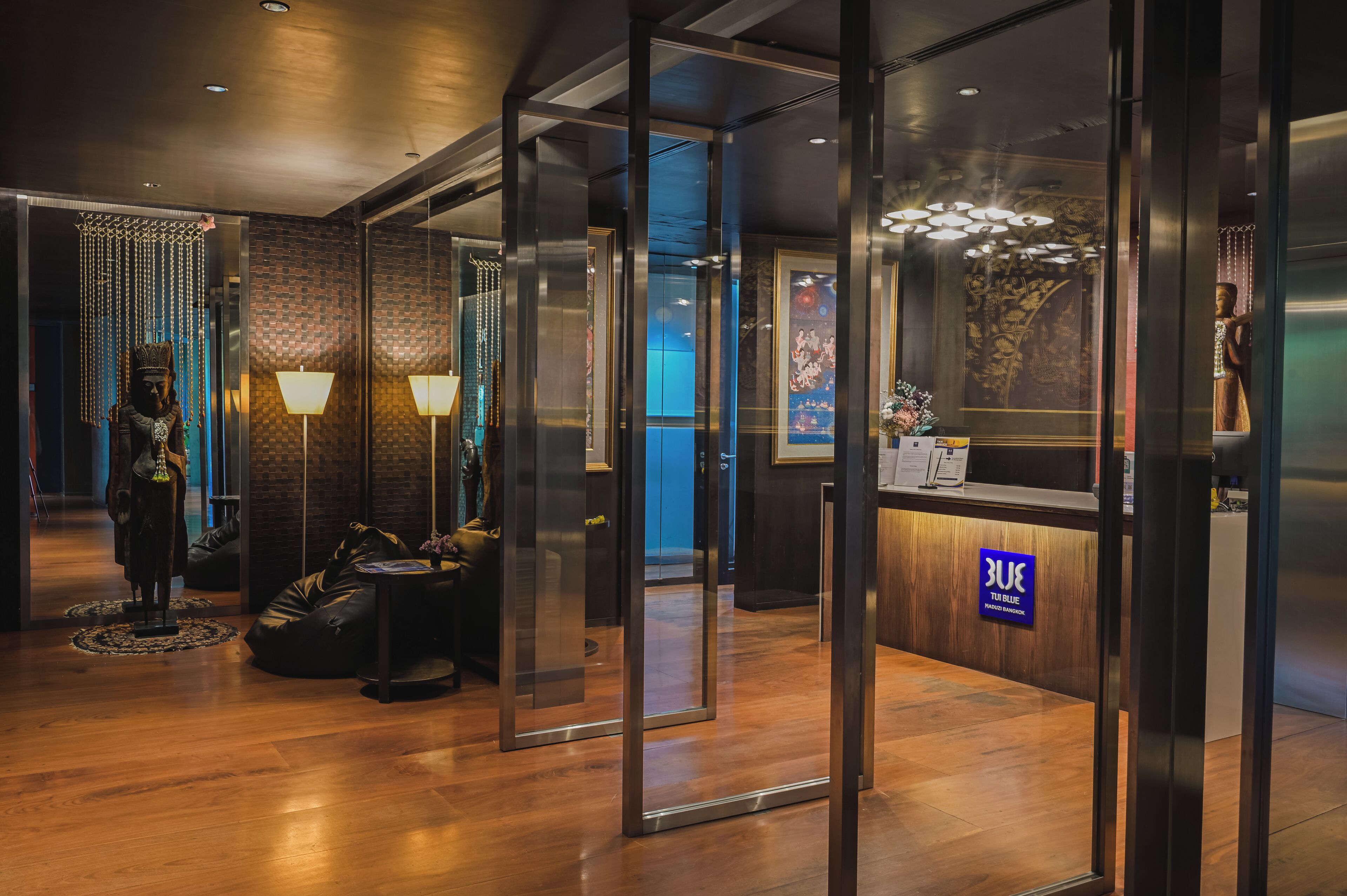 A reception area with a wooden floor, a reception desk with a sign, and a statue.