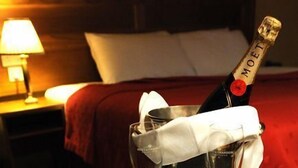 A bottle of Moët champagne in a glass with a napkin, placed on a bed with a red blanket.